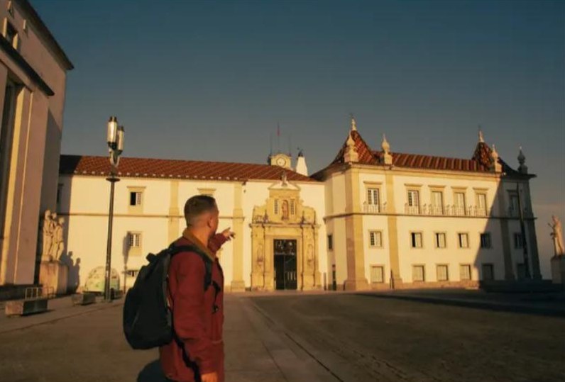 Breno, de mochila preta, apontando para a Universidade de Coimbra